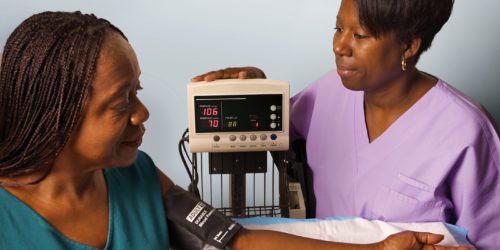 Female Medical Assistant Taking Female Patient's Blood Pressure