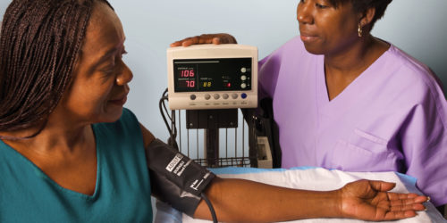 African American Female Medical Assistant Testing African American Female Patient's Blood Pressure