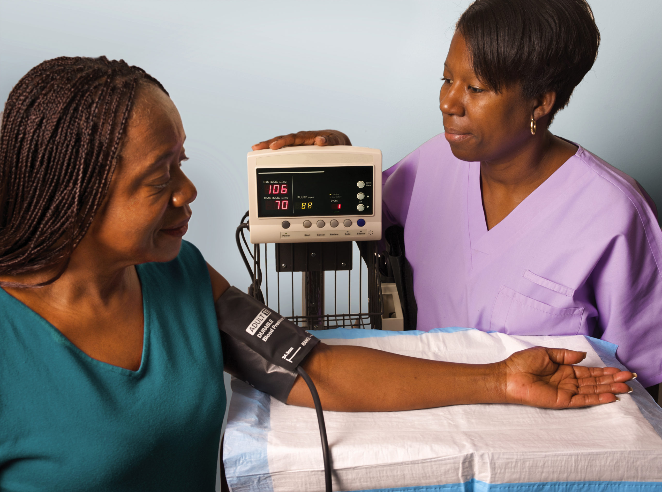 African American female medical assistant testing African American female patient's blood pressure